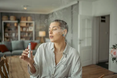 Une femme tenant une vape à la main, dans une maison