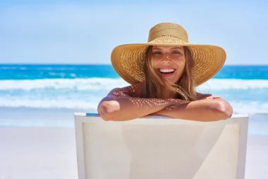 Une femme souriante portant un chapeau sur une plage ensoleillée