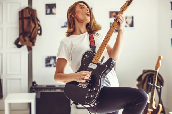 Une jeune femme, fan de rock, jouant de la guitare à la maison.