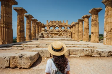 Vue arrière d’une femme avec un chapeau alors qu’elle admire un ancien temple en Sicile