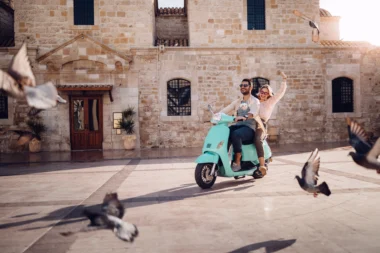 Jeune couple s'amuse au CIRC. Vintage scooter en ville italienne.