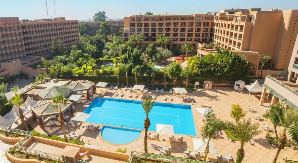 Vue aérienne de l'hôtel Grand Mogador Menara, montrant les bâtiments ainsi que les espaces extérieurs, dont la piscine.