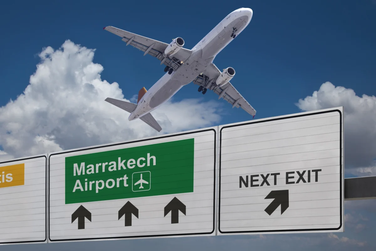 Panneau routier indiquant la direction de l’aéroport de Marrakech et un avion qui vient de se lever.